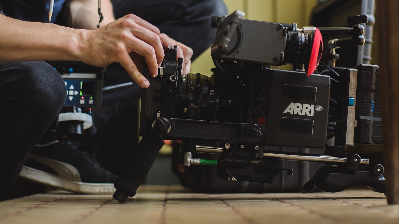 Close-up of hands adjusting a professional ARRI film camera on a production set, showcasing filmmaking equipment.
